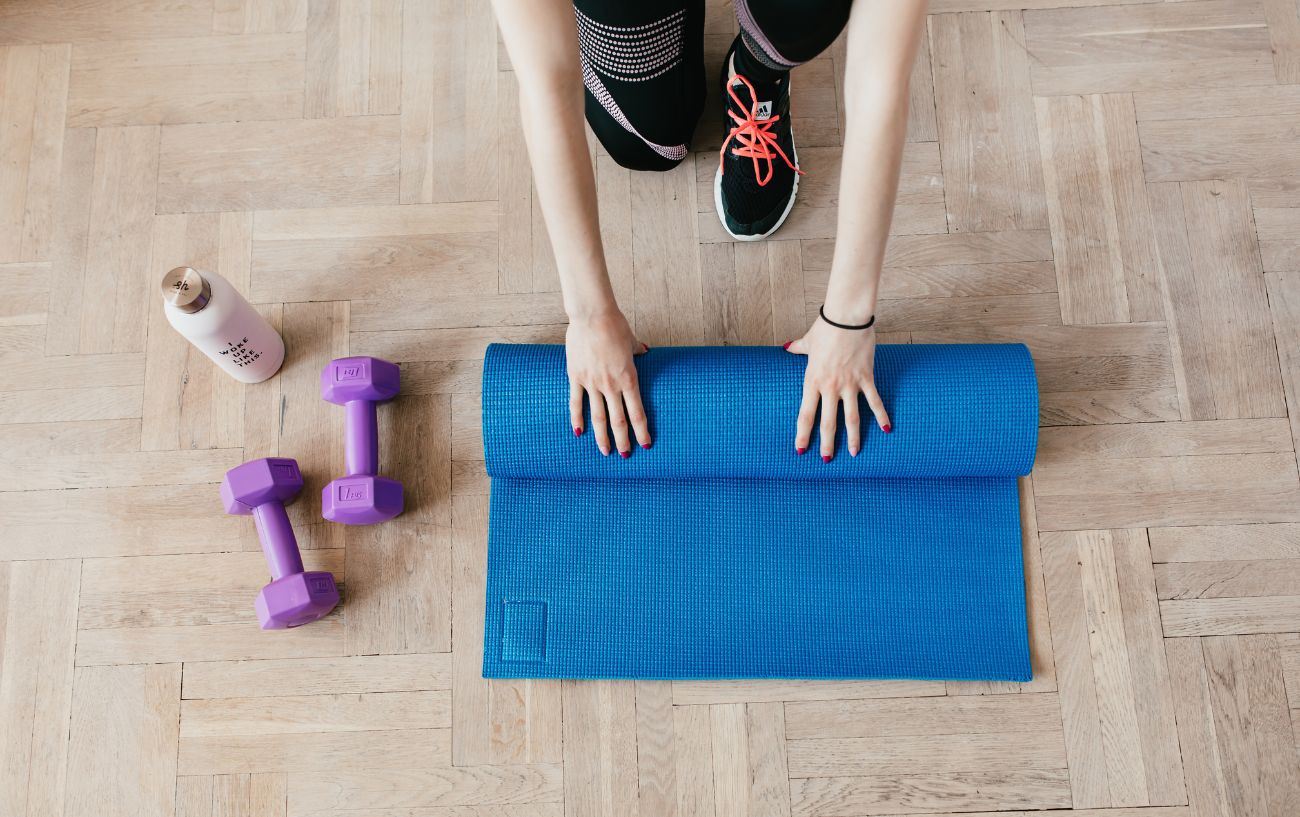 A cyclist rolls out a blue yoga mat as they prepare to improve their flexibility as a method of fixing muscle imbalances.