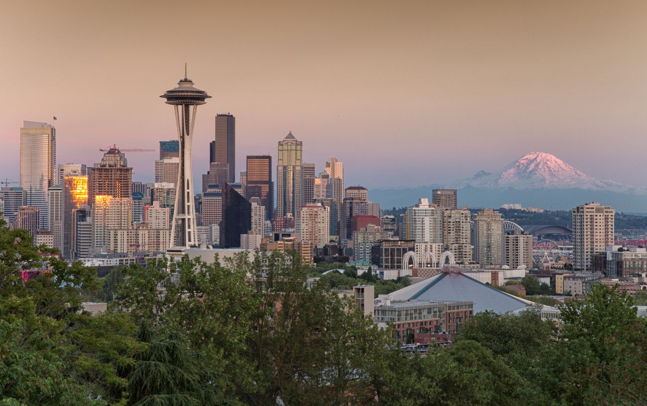Seattle's skyline at sunset, with a mountain in the background.