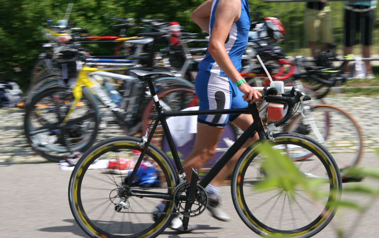 A triathlete runs through the transition zone with his bike.