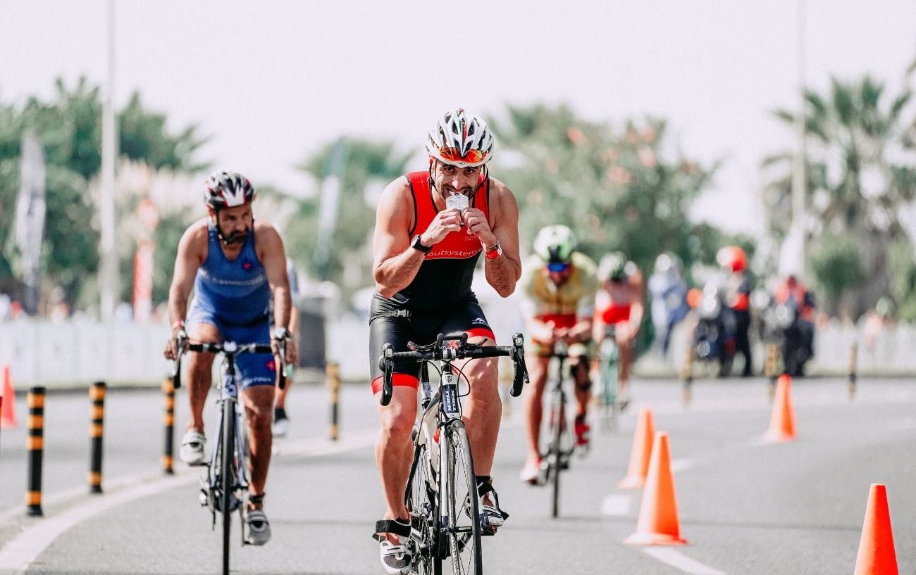 A man on a bicycle eats a gel during a race.
