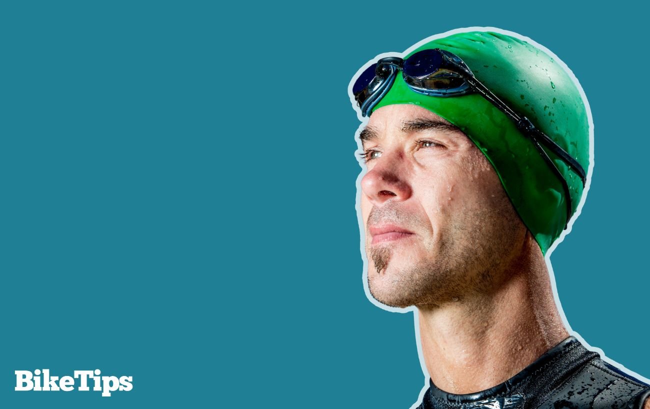 A triathlete in a green swim cap prepares to train for a triathlon.