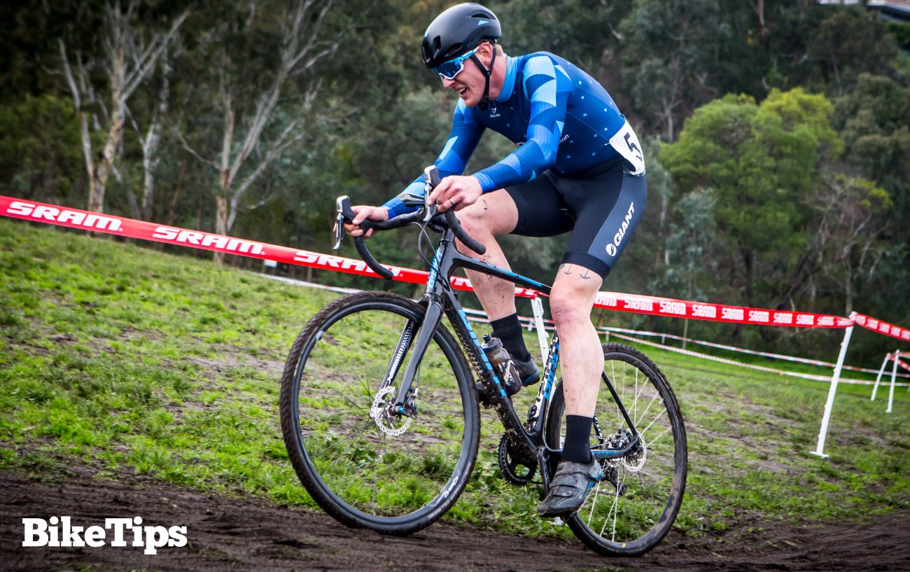 A cyclocross racer riding up a muddy climb.
