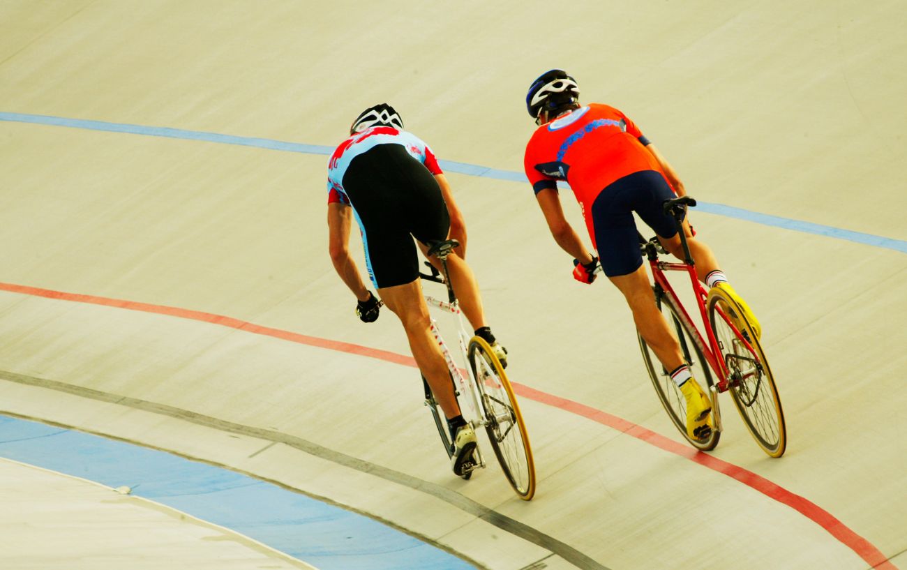 Two amateur track cyclists on a velodrome.