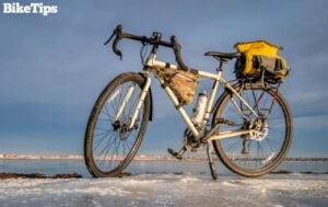 A white winter road bike next to an icy lake.