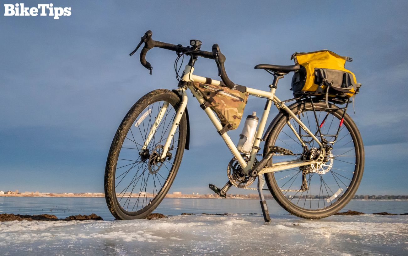 A white winter road bike next to an icy lake.