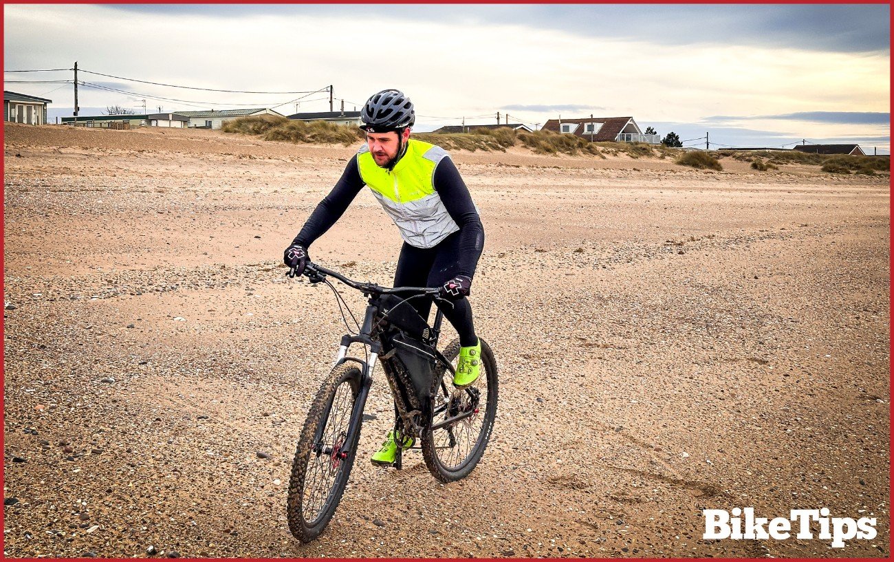 A cyclist riding on the beach.
