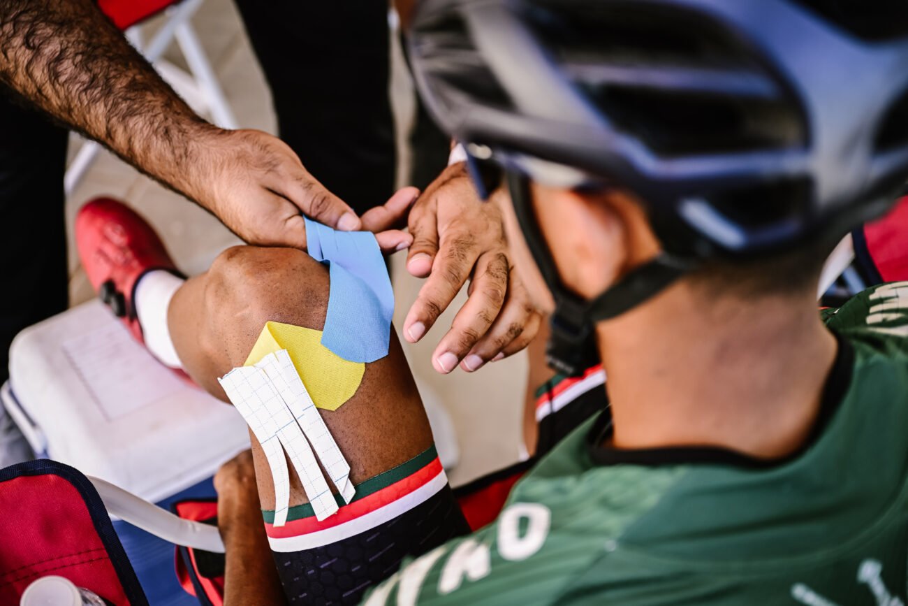A soigneur applies a dressing to a cyclist's wound.