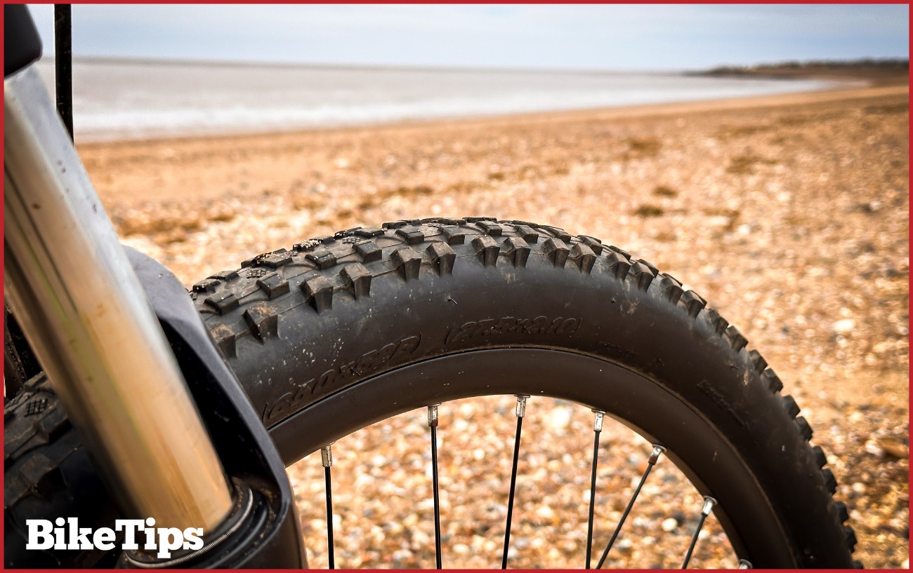 A close up on a bike tire on a beach.