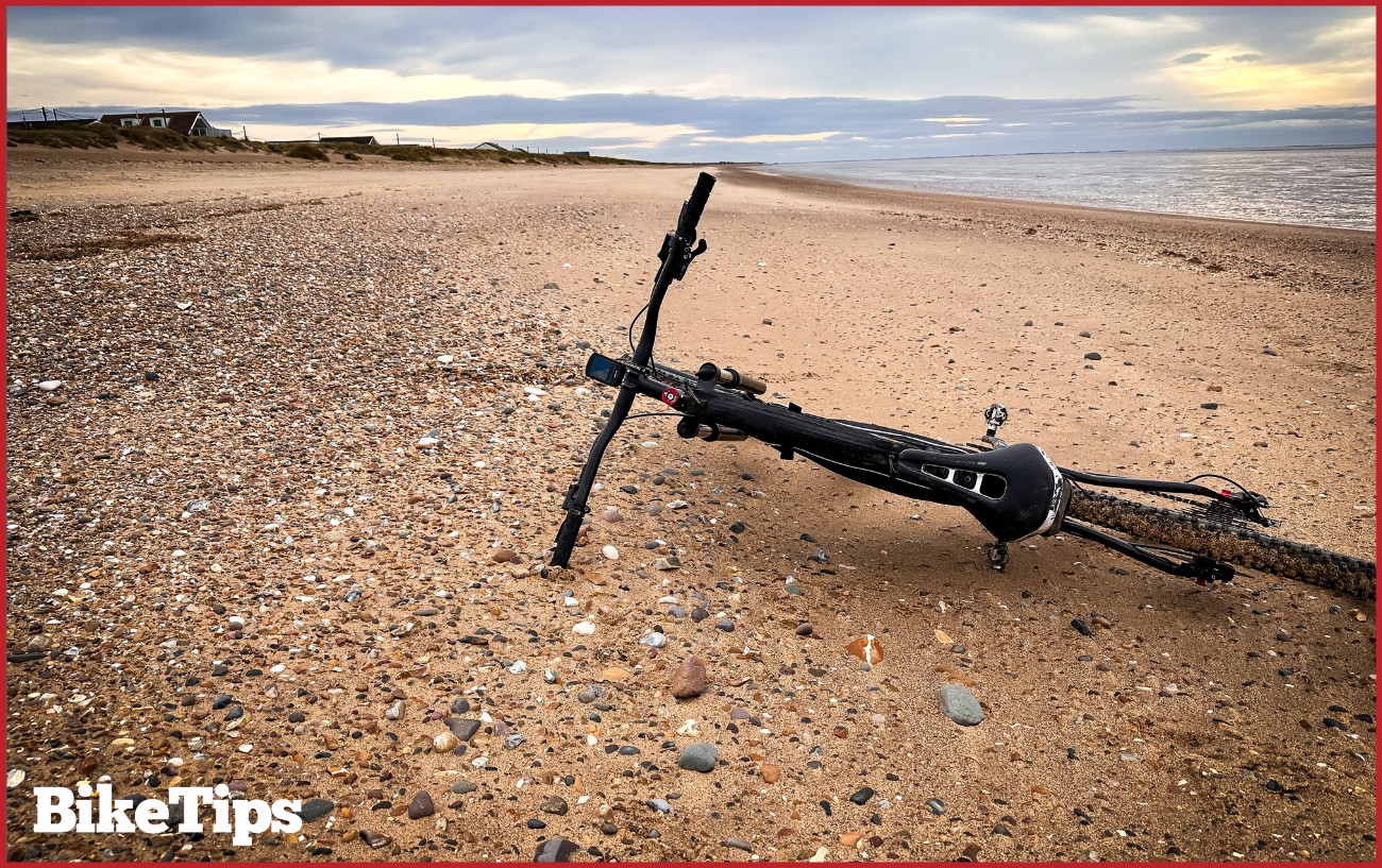 A bike laying down on the beach.