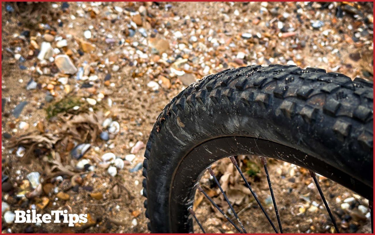 A close up of a mountain bike tire on the beach.