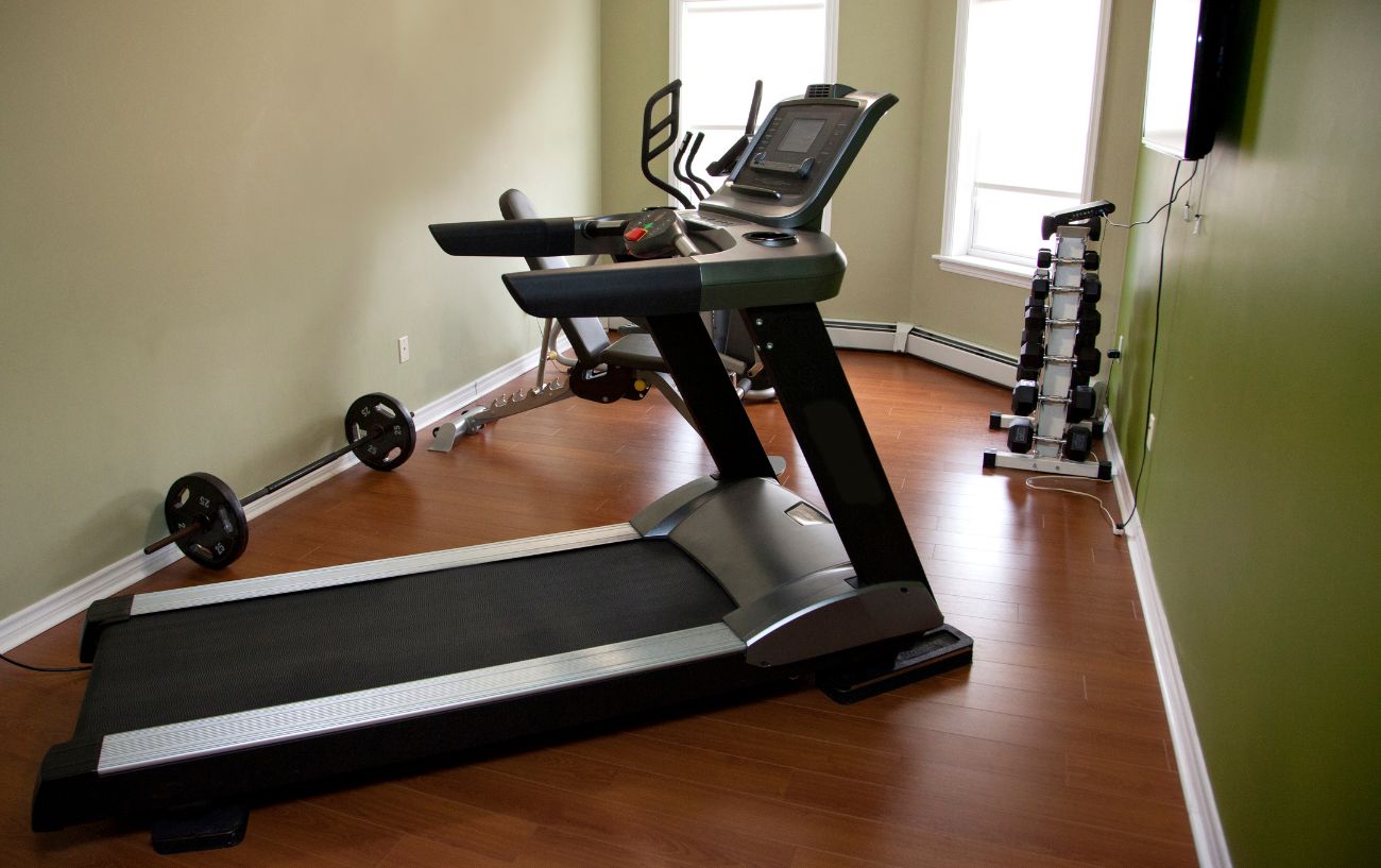 Treadmill on a wooden floor in a home gym.