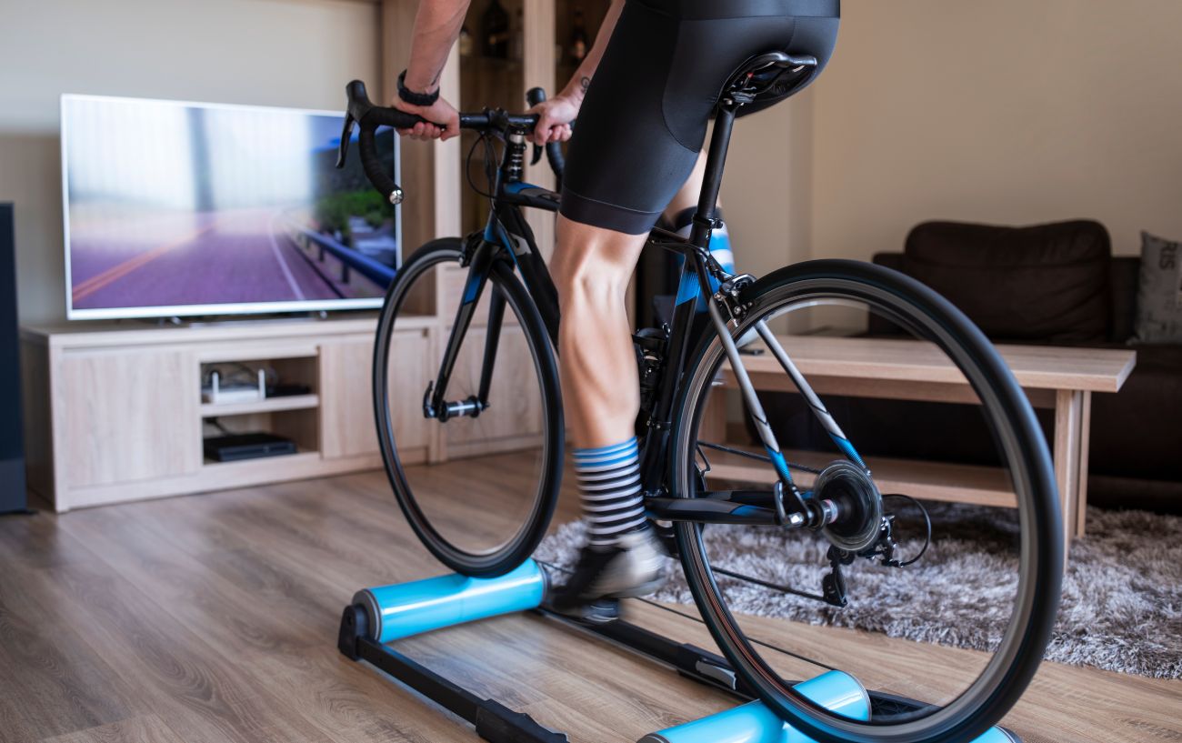 A cyclist using their bike on rollers in their living room.