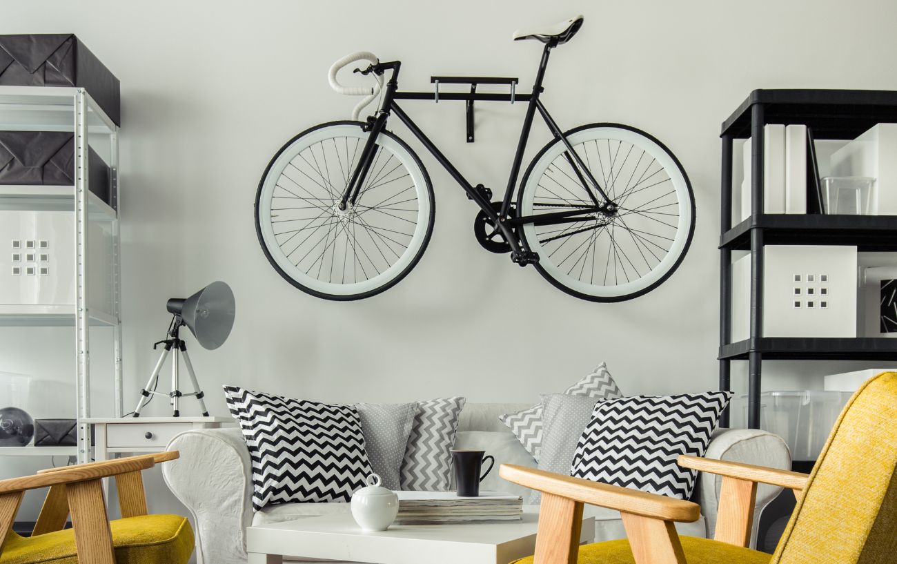 A black bike hangs from a white wall above a sofa.