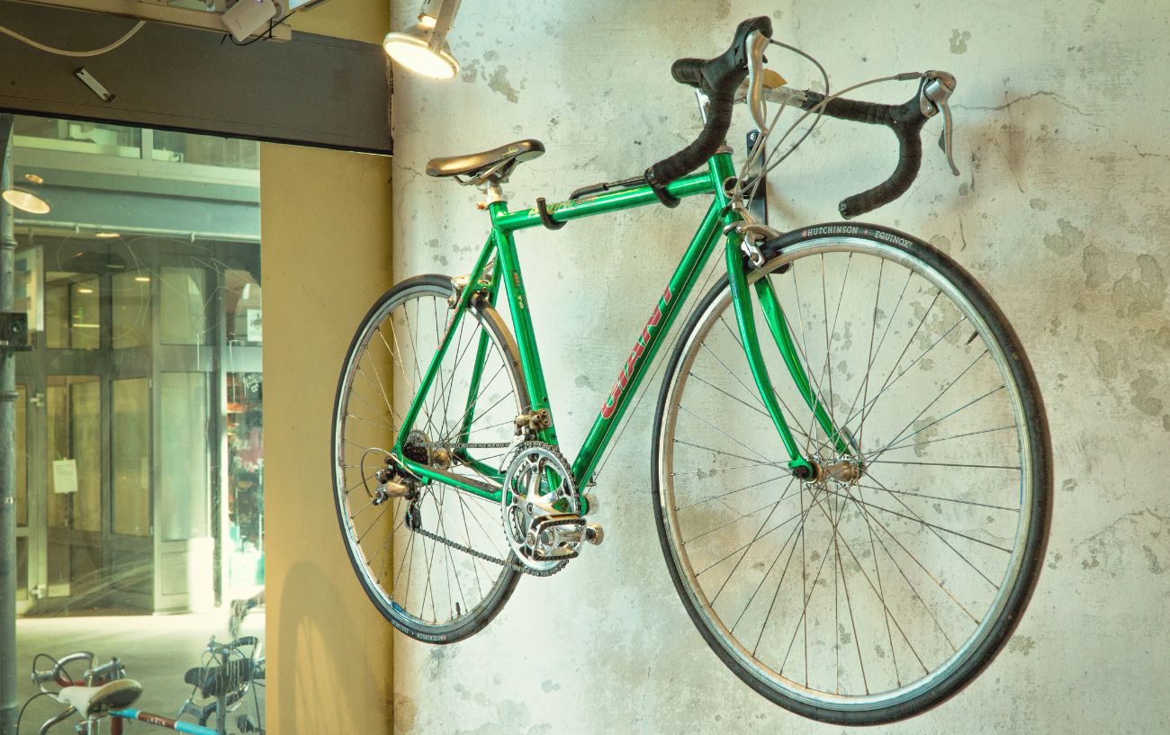 Green steel road bicycle hanging from the wall.