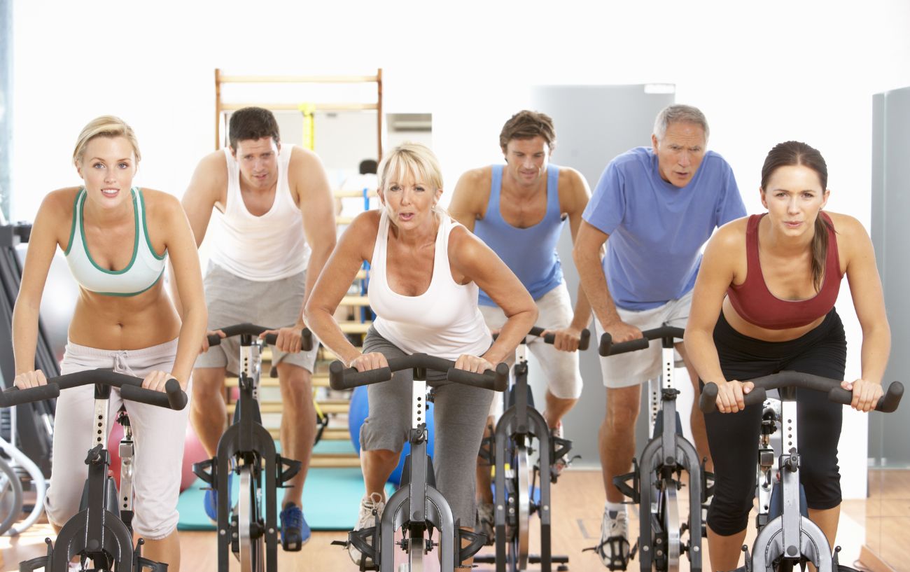 Six people all cycling on indoor bicycles.