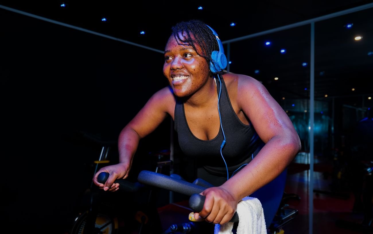 A woman cycles on a indoor bike in a dark room.