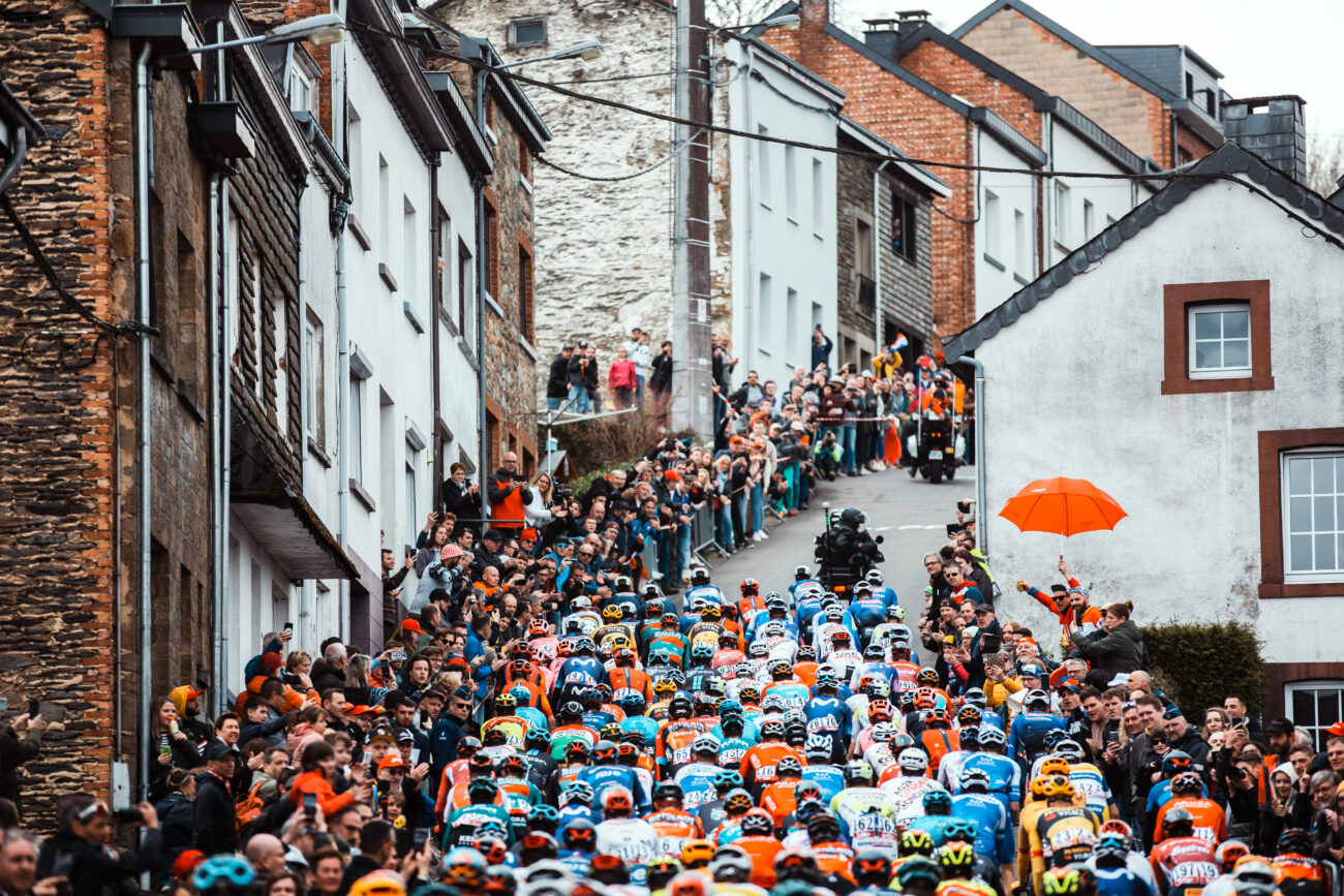 The peloton climbs a steep hill in a village at the 2023 Liege-Bastogne-Liege.