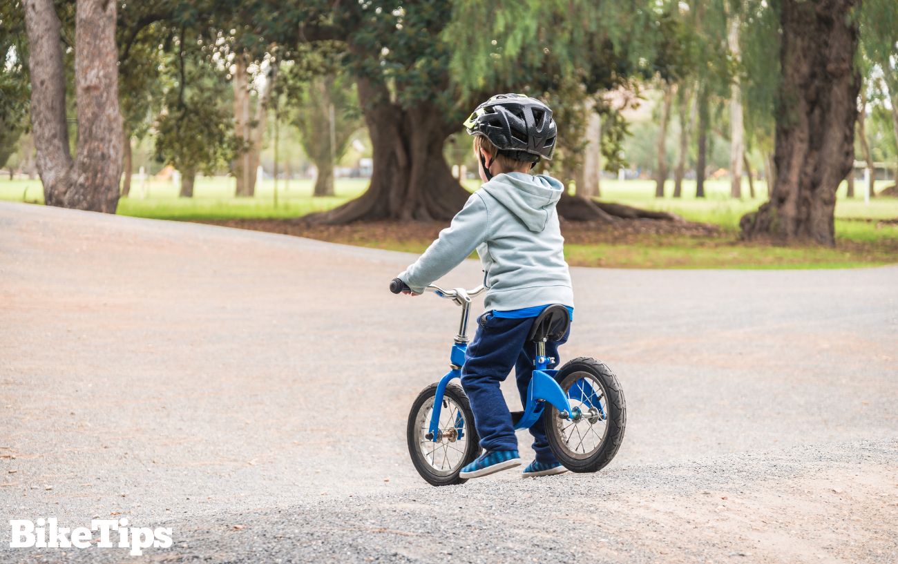 A child on a blue balance bike in a park.