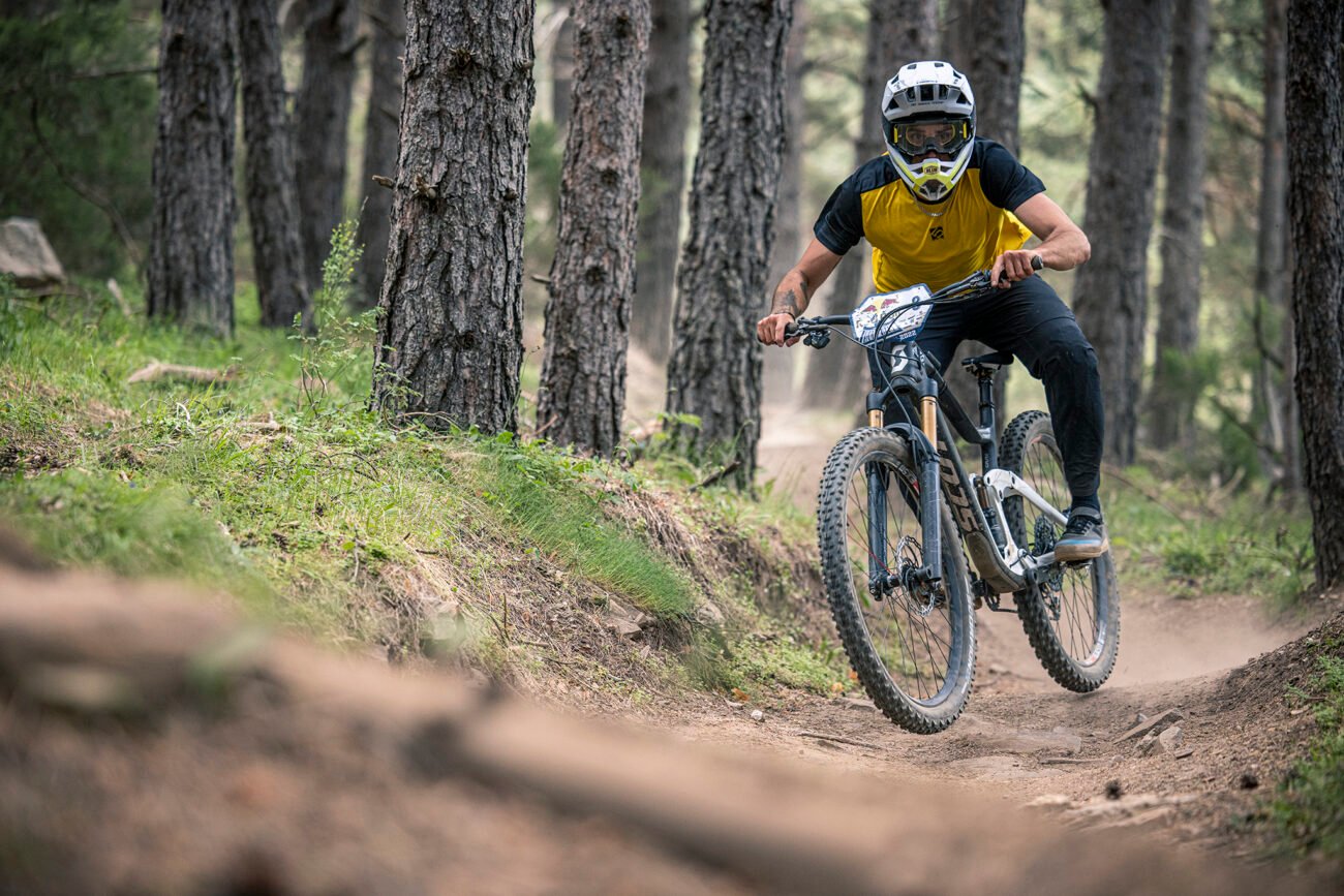 An enduro mountain bike rider charges through a forest.