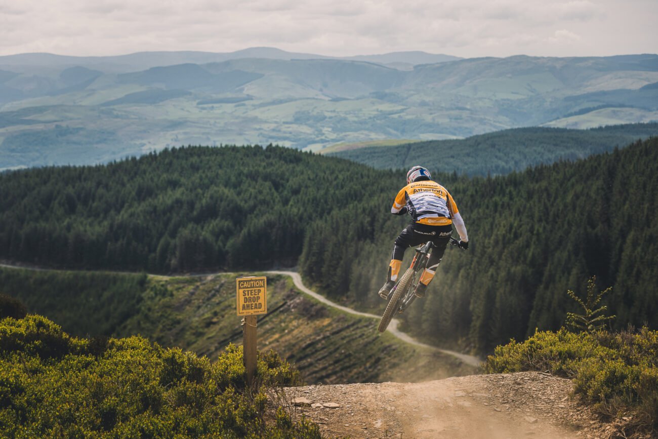 An enduro mountain bike racer takes off from a jump in Wales.