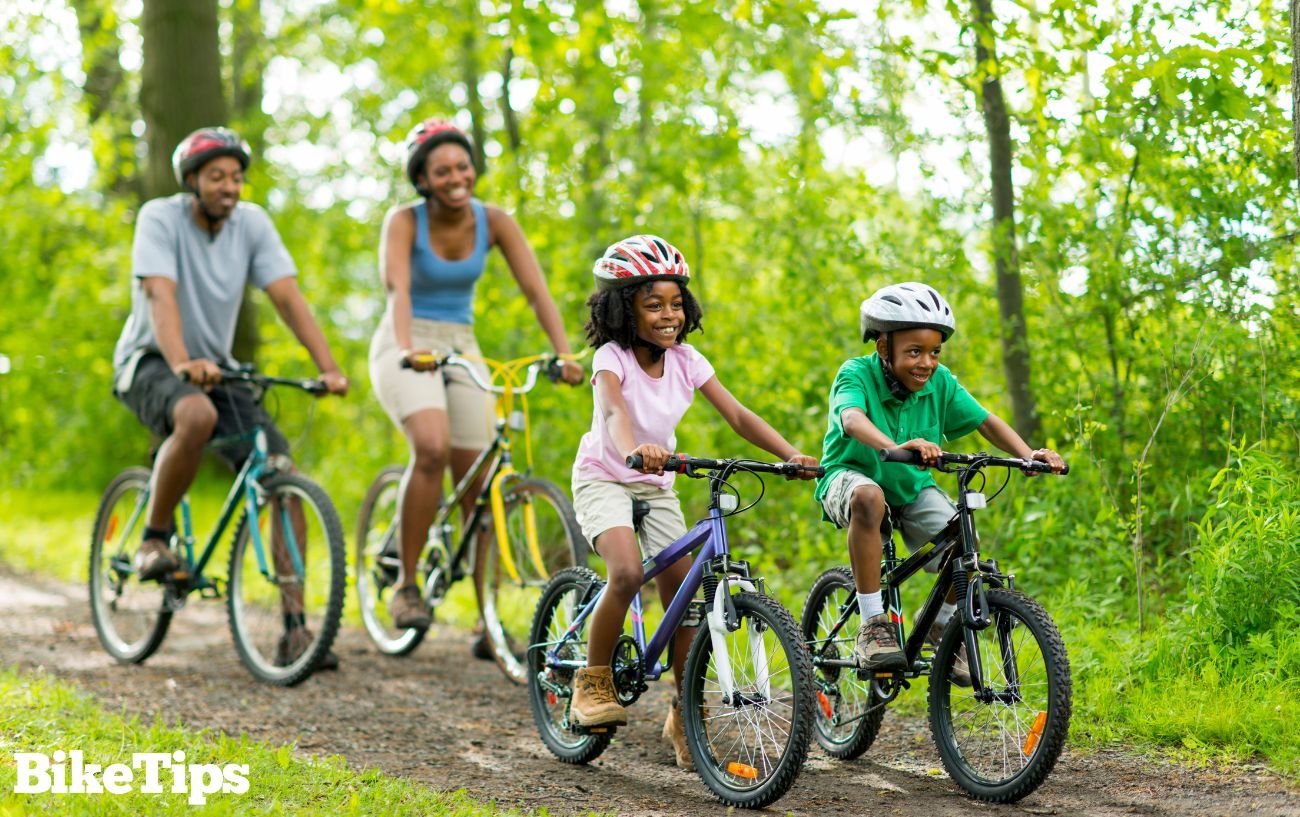 A young family cycling together on a forested bike path.